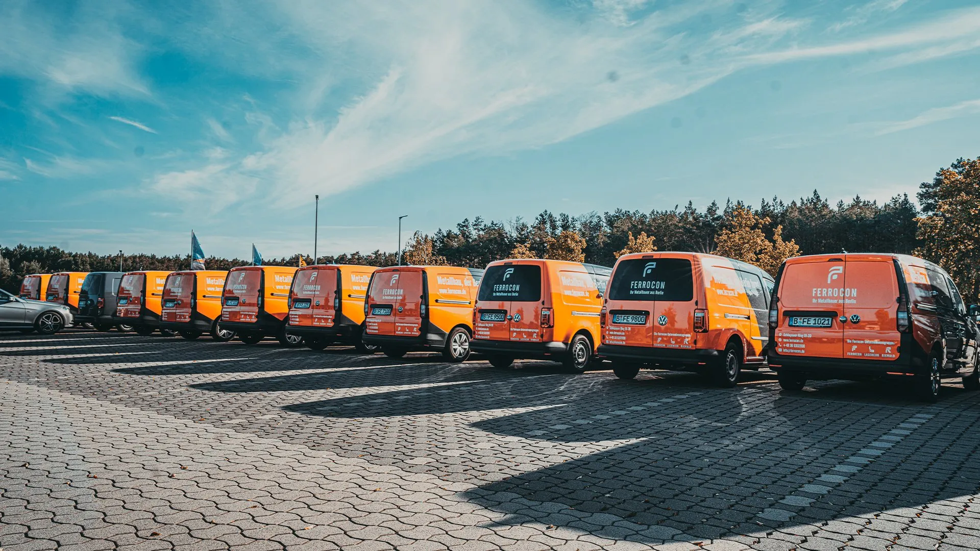 Ferrocon Caddy-Flotte in Orange und Anthrazit in Reihe auf dem Firmenparkplatz